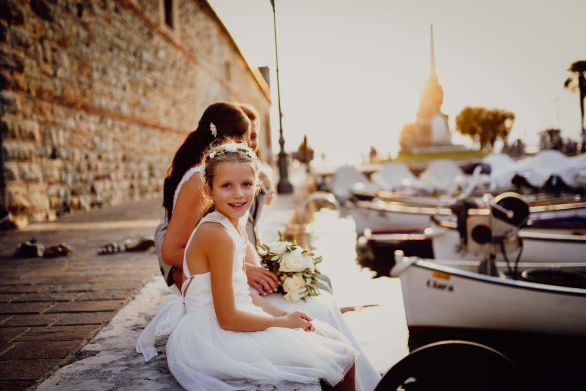 Damigella sorridente seduta accanto alla sposa sul porticciolo al tramonto