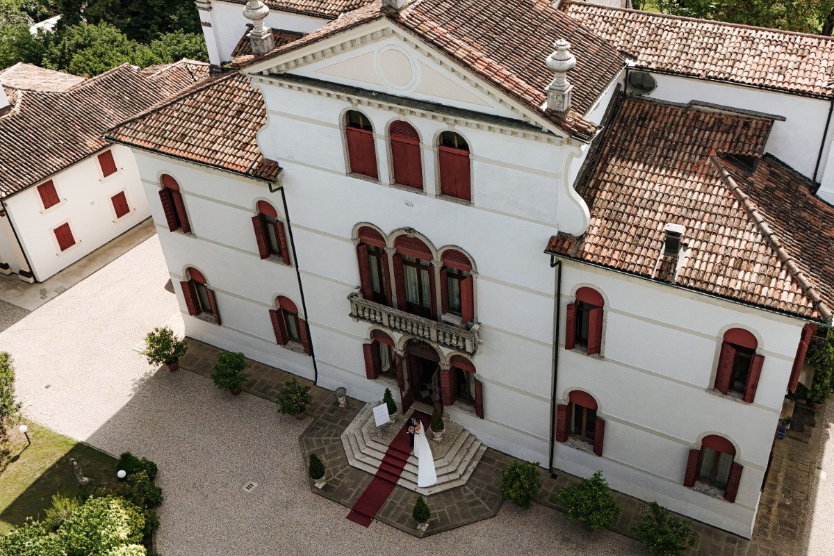 Aerial view of Villa Sagredo in Veneto with the newlyweds on the entrance staircase and the red carpet, photo by Camilla Lovato