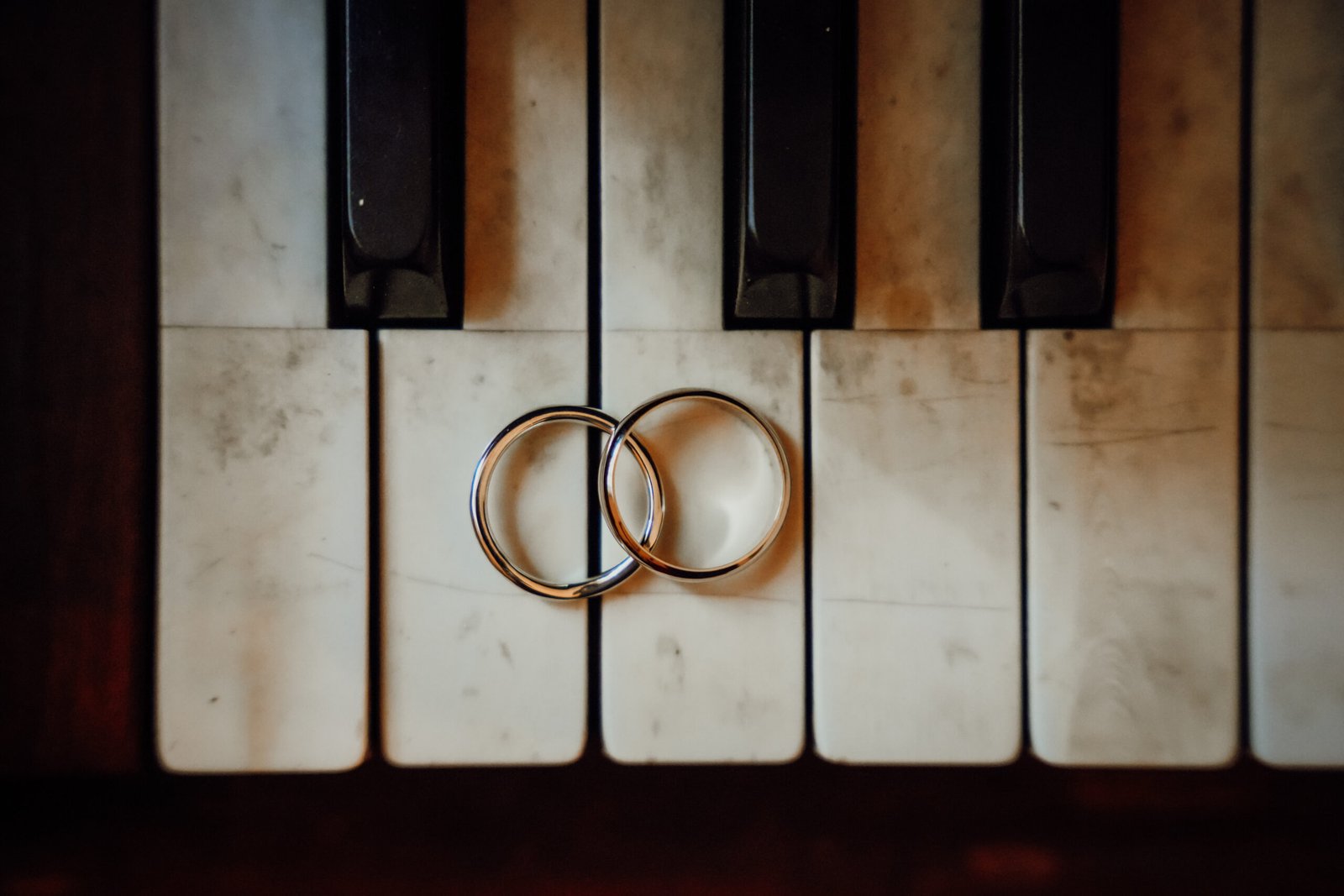 Fedi nuziali appoggiate sui tasti di un pianoforte antico