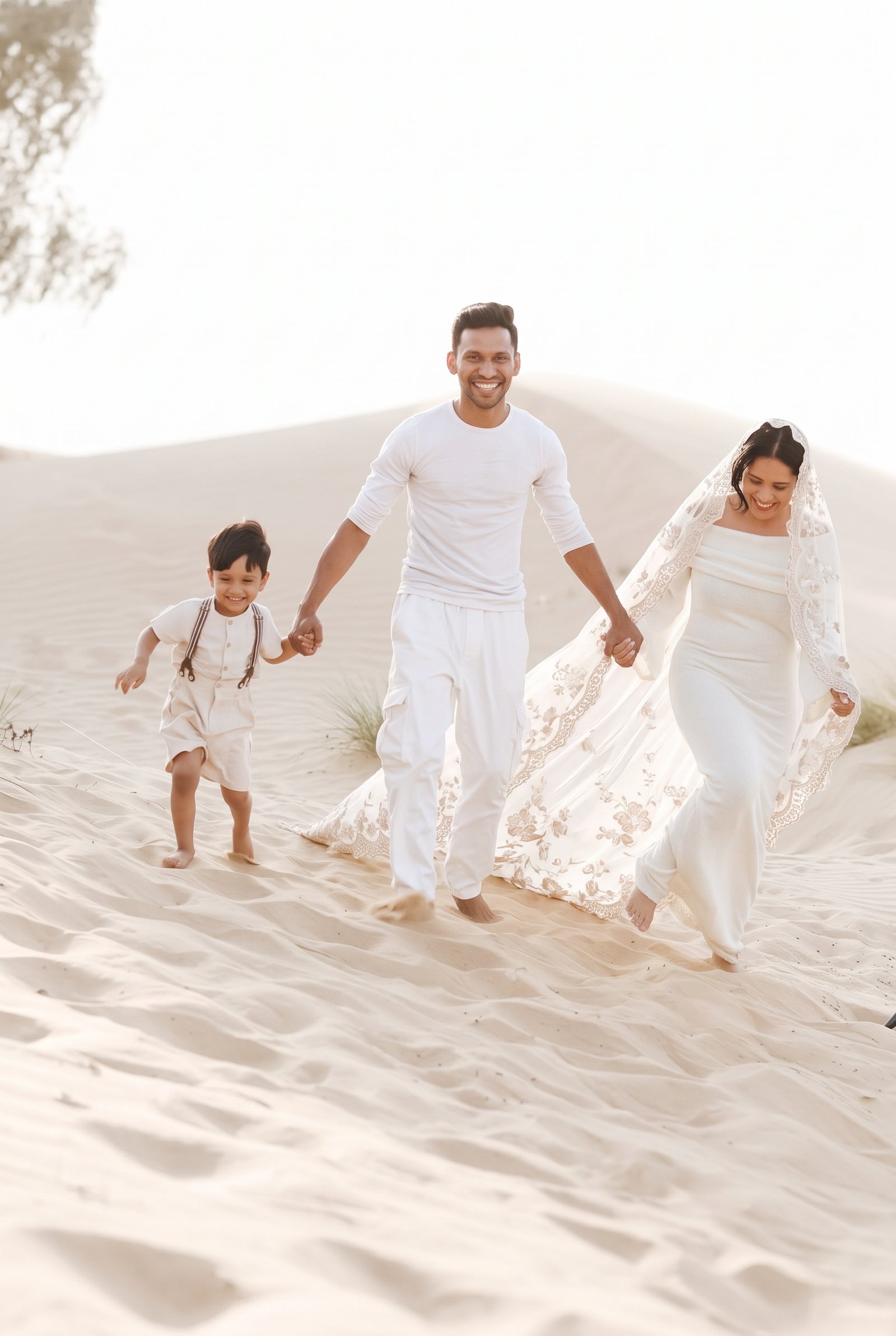Bride, groom, and son running down a dune hand in hand