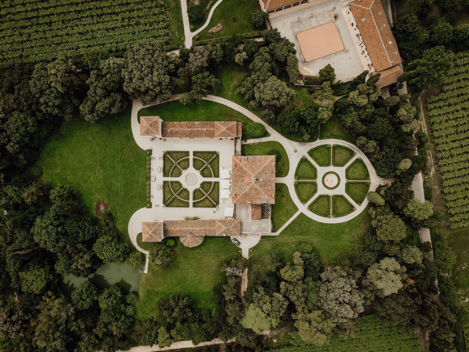 Vista aerea di una villa con giardino all’italiana circondata da vigneti