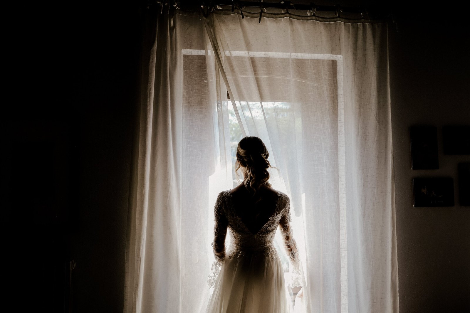 Sposa di spalle in controluce davanti a una tenda bianca